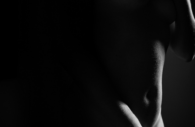 Photographie de nu classique en niveaux de gris d'une jeune femme cachant ses seins et ses organes sexuels